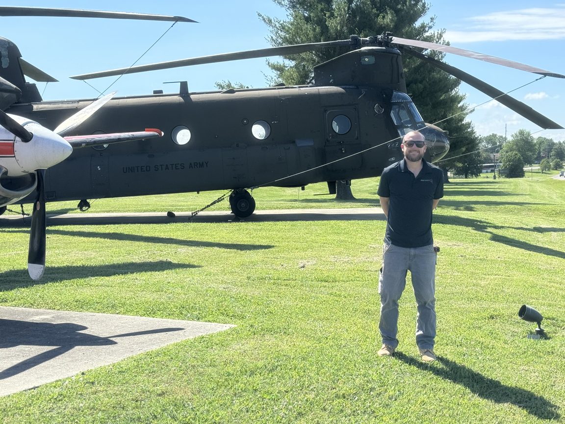 Lunar Inspections founder standing in front of a United States Army Chinook helicopter on a military installation